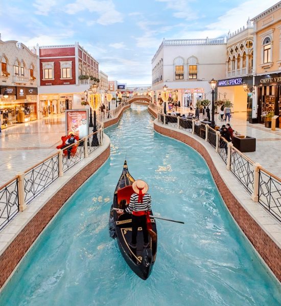 a gondola in the middle of a canal in a shopping district